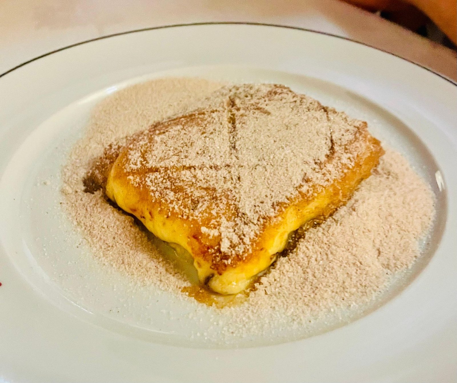 Cartola dessert: fried banana and melted cheese under a thick dusting of cinnamon sugar on a white plate