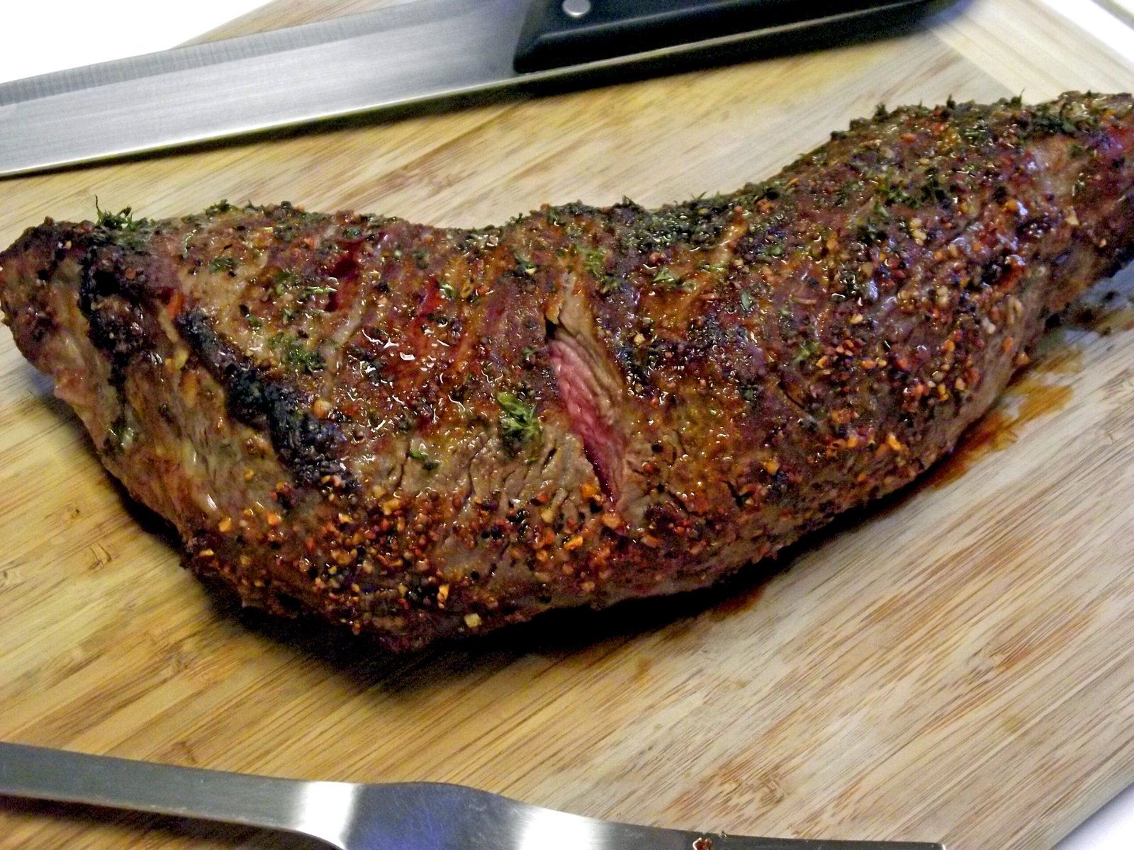 Whole grilled tri-tip roast (maminha) on a cutting board, seared crust, pink center