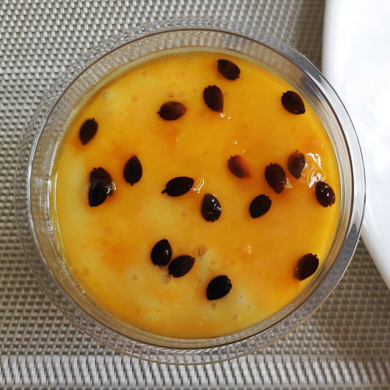 Brazilian passion fruit mousse in a glass bowl, pale yellow cream topped with passion fruit pulp and seeds