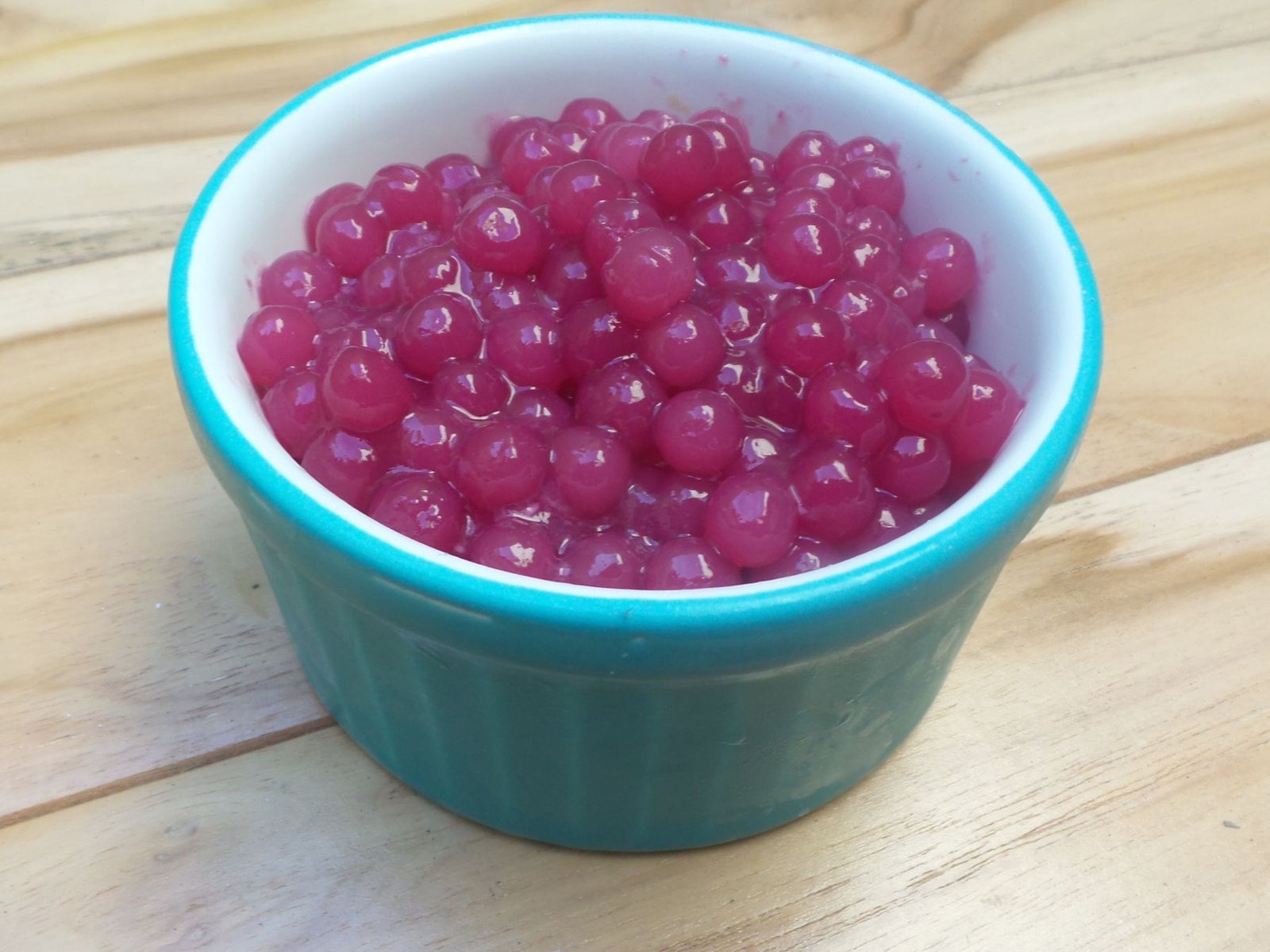Small tapioca pearls cooked in red wine, glossy purple, in a turquoise ramekin